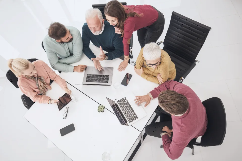 Équipe réunie autour d’une table de travail, vue de dessus.