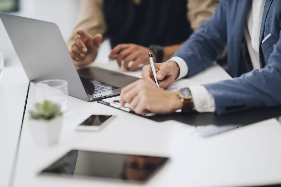 Échange de travail autour d’une table, ordinateurs et carnets.